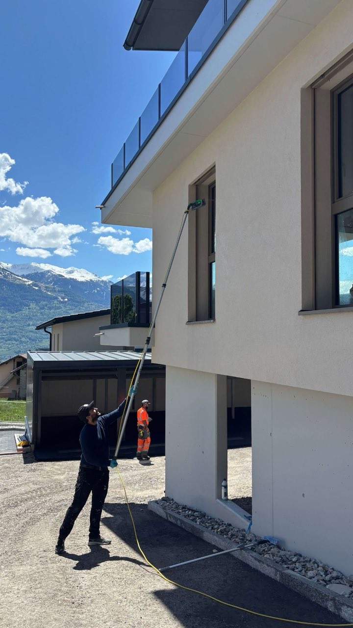 BenFacility Mitarbeiter reinigt eine Glasfassade im Wallis mit Reinwassersystem